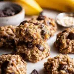 A tray of freshly baked Banana Oatmeal Cookies with dark chocolate chips on parchment paper