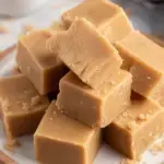 A tray of sliced creamy Brown Sugar Fudge squares on parchment paper.