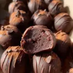 A tray of round chocolate Brownie Protein Bites on parchment paper with mini chocolate chips.
