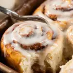 A tray of golden brown Buttermilk Cinnamon Rolls topped with melting cream cheese icing