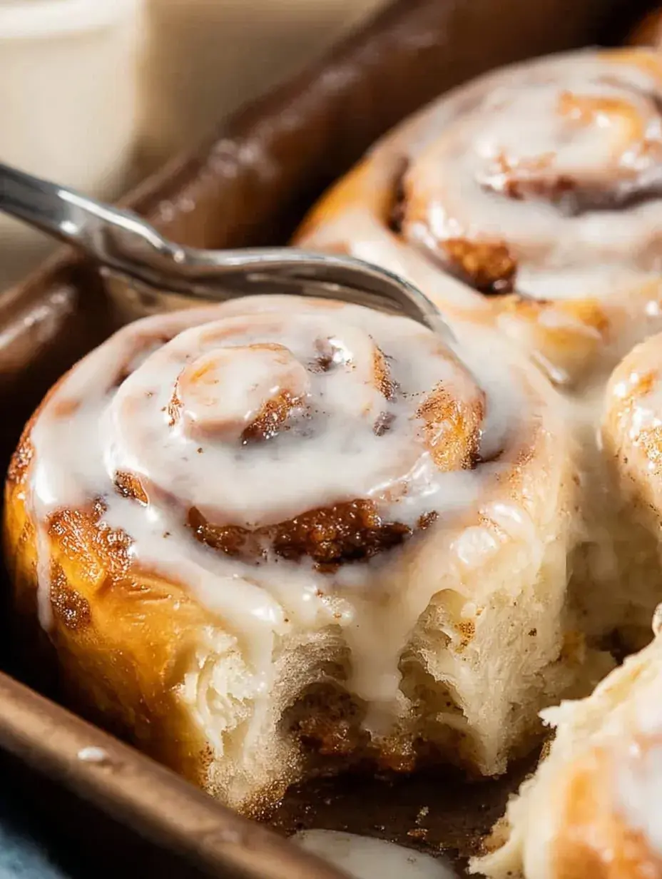 A tray of golden brown Buttermilk Cinnamon Rolls topped with melting cream cheese icing