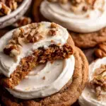 A plate of soft Carrot Cake Cookies topped with swirls of white cream cheese frosting and chopped pecans
