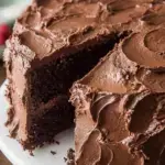 A slice of Classic Moist Chocolate Cake on a white plate showing a tender crumb.