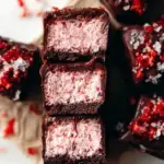 A tray of sliced Chocolate Covered Strawberry Bars with visible layers of pink strawberry cream and dark chocolate ganache
