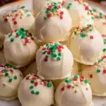 A plate of white chocolate covered Christmas Golden Oreo Truffles with red and green sprinkles.