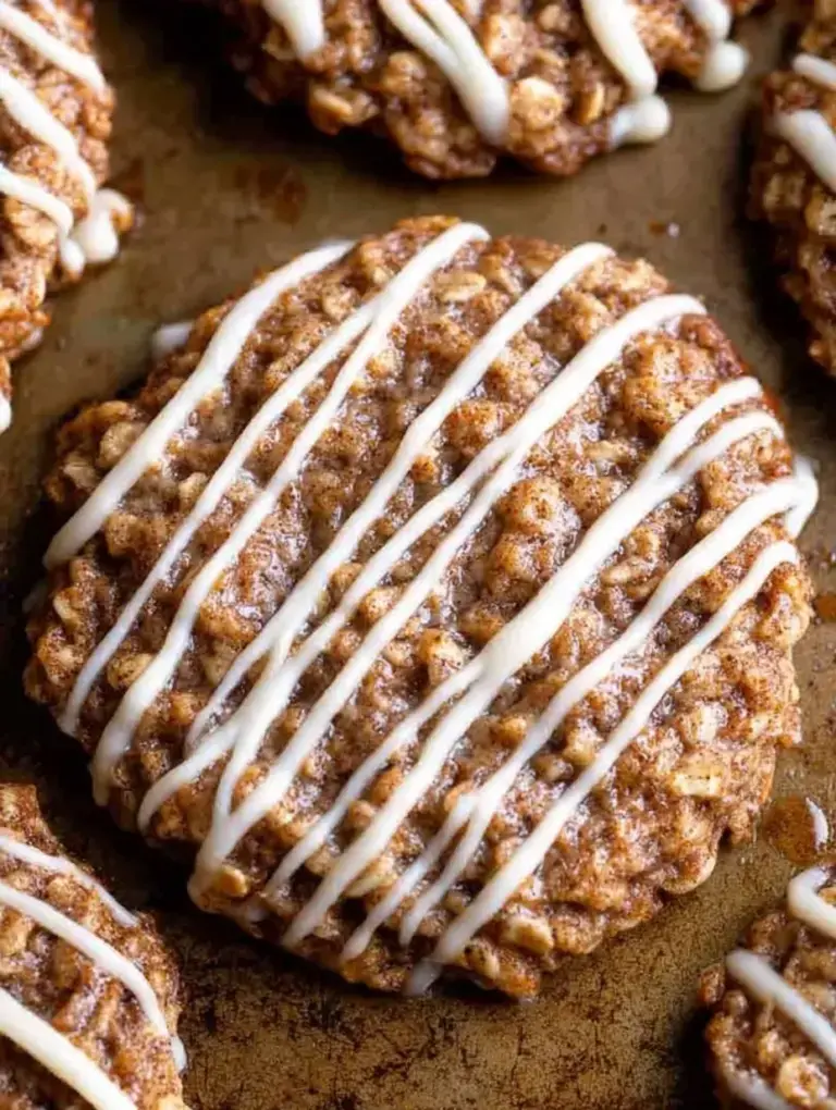 A stack of Cinnamon Roll Oatmeal Cookies drizzled with white vanilla glaze on a cooling rack.