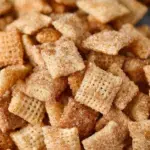 A bowl of golden Cinnamon Sugar Chex Mix with a sparkly sugar coating