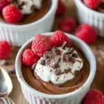 A close up shot of Classic Chocolate Mousse in a glass ramekin topped with whipped cream and chocolate shavings.