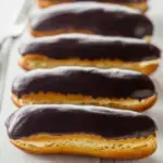 Golden Classic Chocolate Eclairs filled with vanilla cream and topped with shiny chocolate glaze