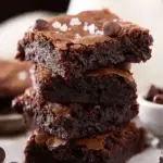 A stack of freshly baked Cocoa Powder Brownies with shiny tops and fudgy centers on a wire rack.