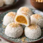 White Coconut Peanut Mochi balls on a plate coated in desiccated coconut
