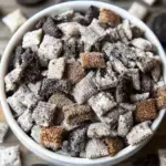 A bowl of Cookies and Cream Muddy Buddies coated in white chocolate and cookie crumbs.