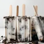 Six Vegan Cookies and Cream Popsicles in molds with cookie crumbs on top