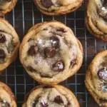 Freshly baked Crispy and Chewy Chocolate Chip Cookies on a wire rack with melting chocolate chips