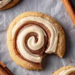 Large Crumbl Cinnamon Swirl Cookies with a spiral of cream cheese frosting on a baking sheet