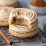Large Crumbl Snickerdoodle Cupcake Cookies with a thick swirl of cream cheese frosting on a cooling rack