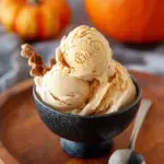 A scoop of creamy Dairy-Free Paleo Pumpkin Ice Cream in a bowl with a sprinkle of cinnamon