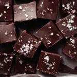 A platter of sliced Dark Chocolate Sea Salt Vegan Fudge topped with flaky salt