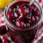A small glass jar filled with glossy easy cherry sauce showing whole cherries and a thick red syrup.