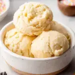 A bowl of creamy edible sugar cookie dough with a silver spoon