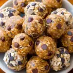 A plate of round Classic Oatmeal Peanut Butter Energy Balls with chocolate chips visible in the texture.