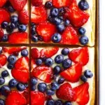 A colorful Classic Fruit Pizza with strawberries, kiwi, and blueberries on a sugar cookie crust.