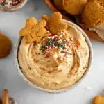 A bowl of creamy Gingerbread Cookie Dip surrounded by apple slices and gluten-free cookies