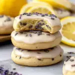 A stack of Glazed Lemon Lavender Cookies with a smooth white citrus icing and dried lavender buds on top.