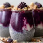 A glass jar layered with Gluten-Free Blackberry Cobbler Chia Pudding and a toasted oat crumble top