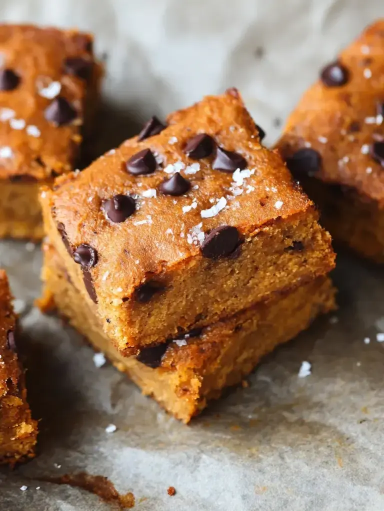A stack of chewy Gluten-Free Blondies with melty chocolate chips on a wooden board.