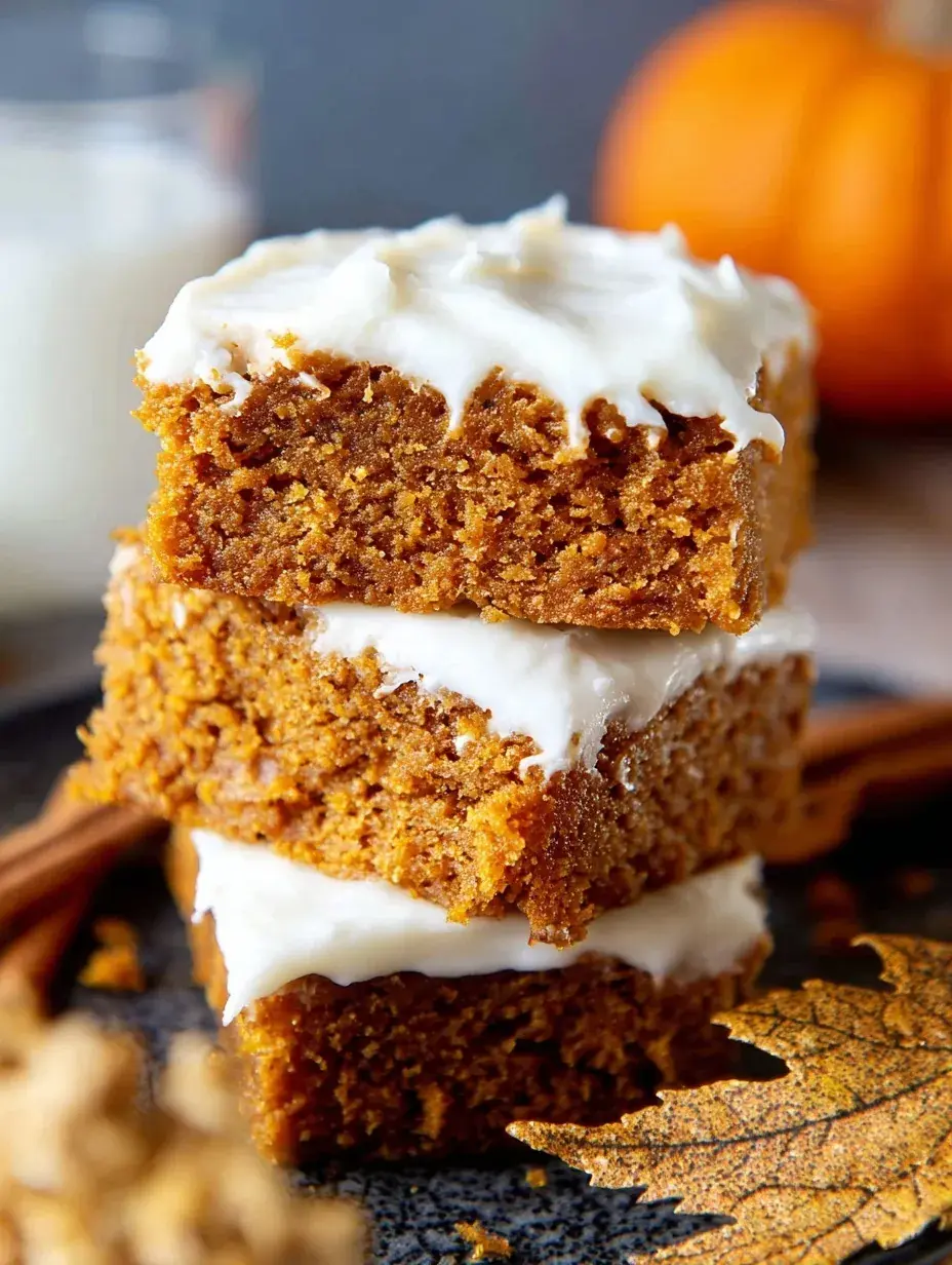 A close up of sliced Gluten-Free Pumpkin Squares with thick cream cheese frosting on a wooden board