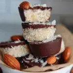 A plate of homemade healthy almond joys with dark chocolate coating and a whole almond on top