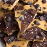 A tray of broken pieces of Healthy Cookie Dough Bark topped with melted dark chocolate and flaky sea salt.