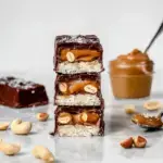 A stack of sliced Healthy Snickers Protein Bar showing layers of nougat, caramel, and peanuts
