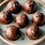 A platter of Juicy Chocolate Chip Cookie Dough Truffles with one bitten open to show the soft center