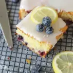 A slice of Lemon Blueberry Sheet Cake with thick cream cheese frosting and fresh berries
