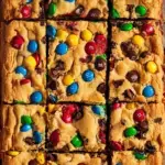 A stack of chewy M&M Cookie Bars showing the soft center and colorful candy topping.