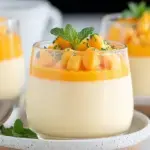 A close up of individual glasses of Mango Panna Cotta topped with bright yellow fruit puree