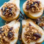 Warm Maple Pecan Baked Pears topped with toasted nuts and golden syrup in a baking dish.