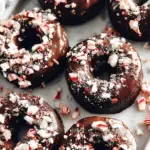Baked Medjool Date Chocolate Peppermint Donuts with dark chocolate glaze and crushed candy canes on a wire rack