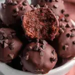 A tray of small round No-Bake Brownie Bites on parchment paper with cocoa powder dusting