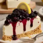 A slice of No-Bake Lemon Blueberry Cheesecake with purple berry swirls and a graham cracker crust