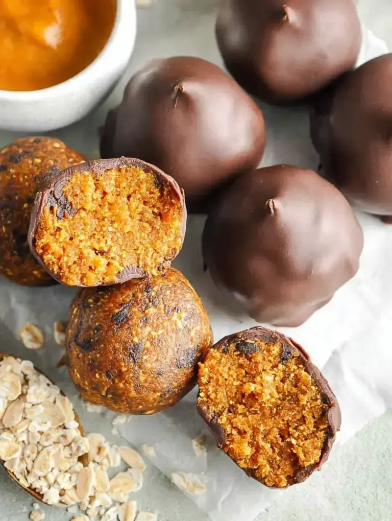 A plate of round No-Bake Pumpkin Bites with mini chocolate chips sitting on a wooden table.
