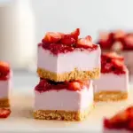 Chilled No-Bake Strawberry Cheesecake Bars topped with fresh sliced strawberries and a shiny glaze