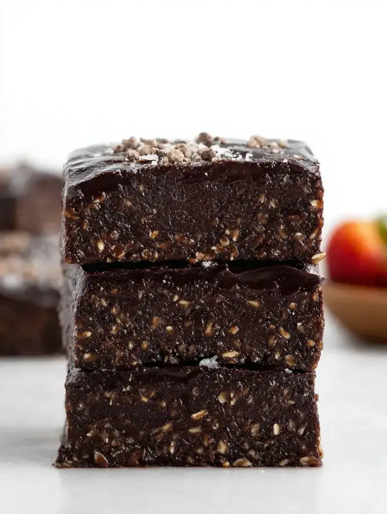 A square of dark, fudgy No-Bake Vegan Brownies topped with chocolate chips on a wooden board.
