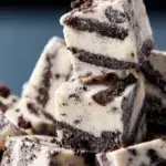 A plate of sliced white chocolate Oreo Fudge with crushed cookies on top