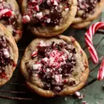 Freshly baked Peppermint Chocolate Chip Cookies topped with crushed candy canes on a cooling rack