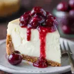 A slice of Classic New York Style Cheesecake on a plate with a golden graham cracker crust