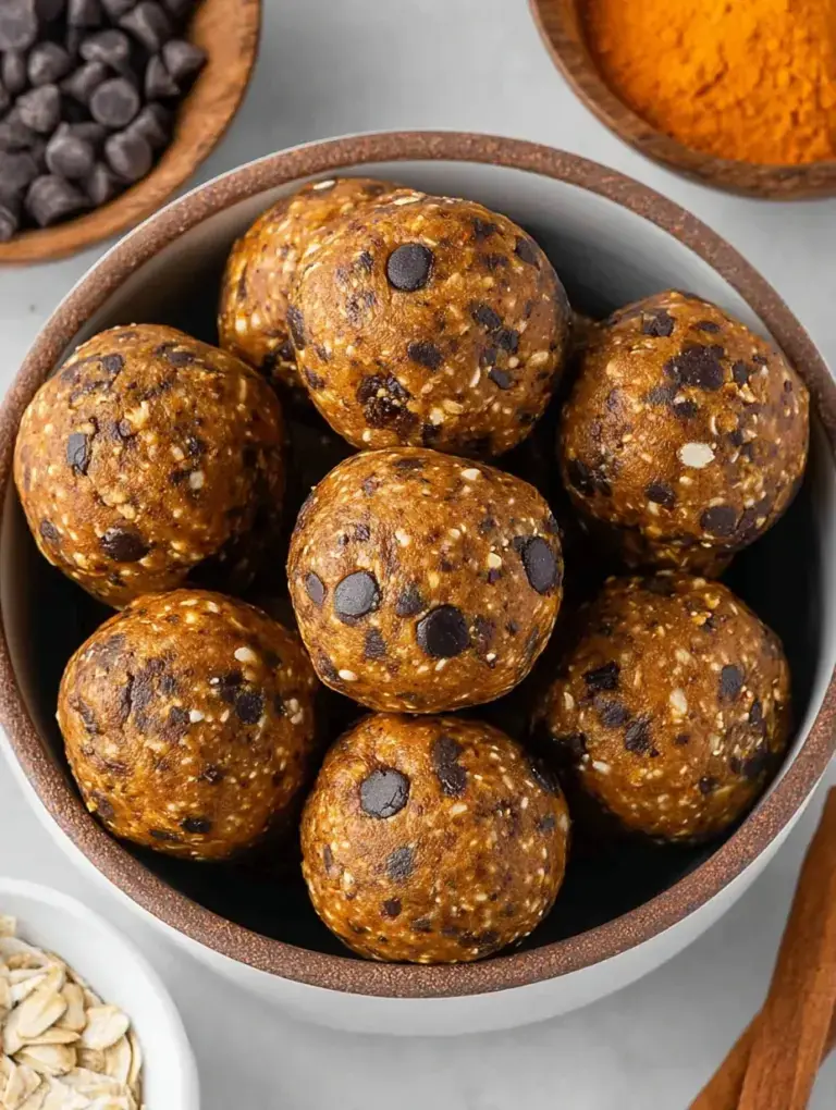 A tray of round Pumpkin Energy Balls with mini chocolate chips arranged in a cozy kitchen setting.