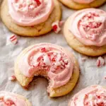 Soft white Peppermint Meltaways topped with pink frosting and crushed candy canes on a holiday tray